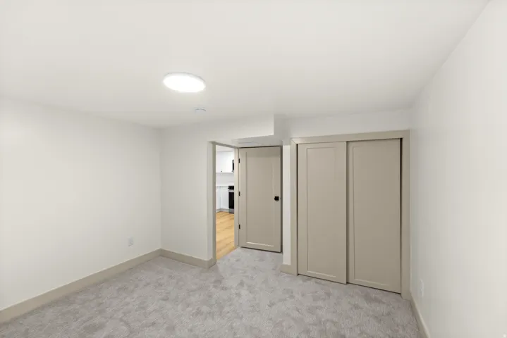 Neutral-toned room featuring a soft gray carpet, white walls, and a recessed ceiling light fixture