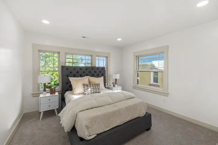 Bedroom featuring light gray carpeting, neutral wall paint, recessed lighting, and multiple windows with light-colored trim