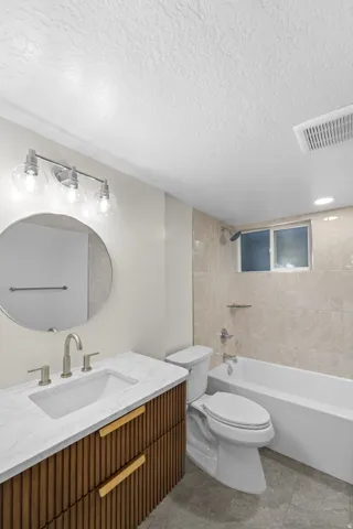 Bathroom featuring a contemporary wood-finish vanity with gold-tone hardware, a white rectangular undermount sink, and a light-toned countertop