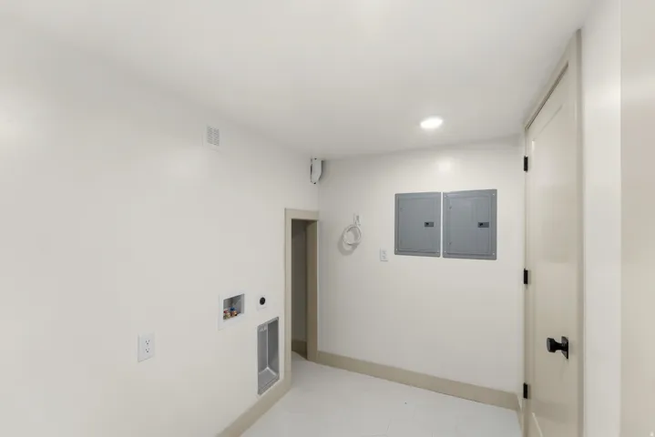 Dedicated utility area featuring white hexagonal floor tiles, a recessed ceiling light, and light beige baseboards
