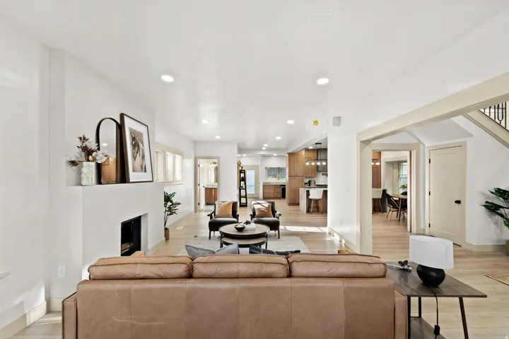 Living area featuring light wood-finish flooring, recessed lighting, and a prominent fireplace with a hearth