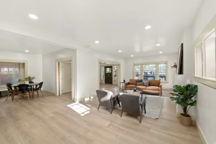 Bright living area featuring light wood-finish flooring, recessed lighting, and white walls with contrasting trim