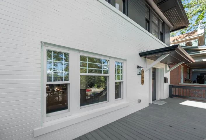 White painted brick exterior with multiple sash windows, a dark grey porch, a covered entryway, and a black wall sconce