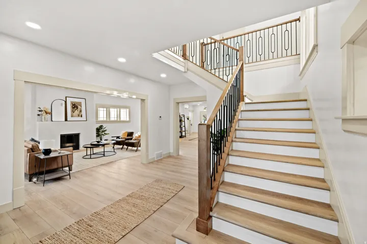 Grand staircase featuring wood-finish treads, white risers, and a contemporary wrought iron baluster system