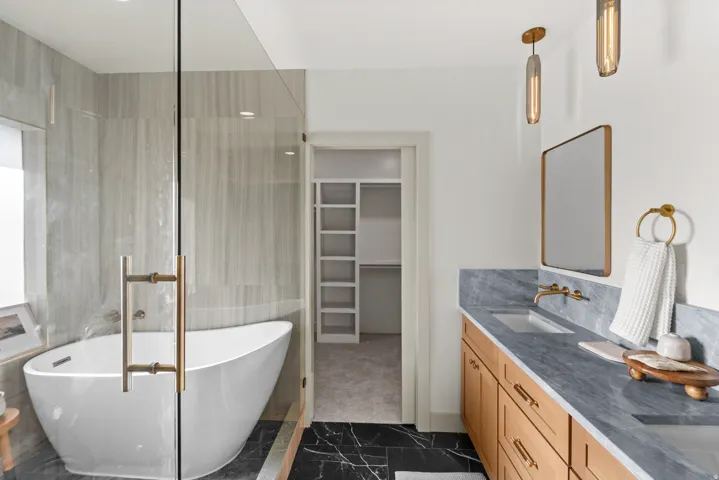 Freestanding bathtub within a glass-enclosed shower featuring large format wall tile