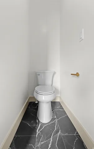 White commode with a round bowl and tank, set against white walls