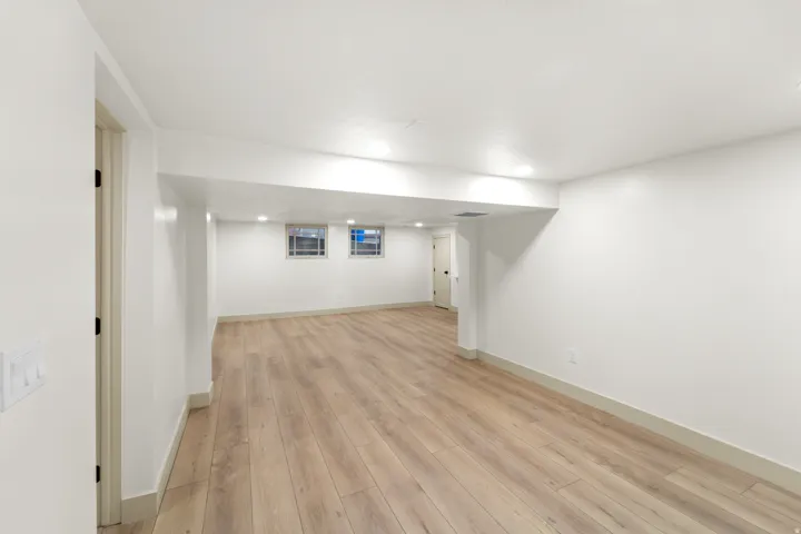 Open space featuring wood-finish flooring, white painted walls, recessed lighting, and two small windows