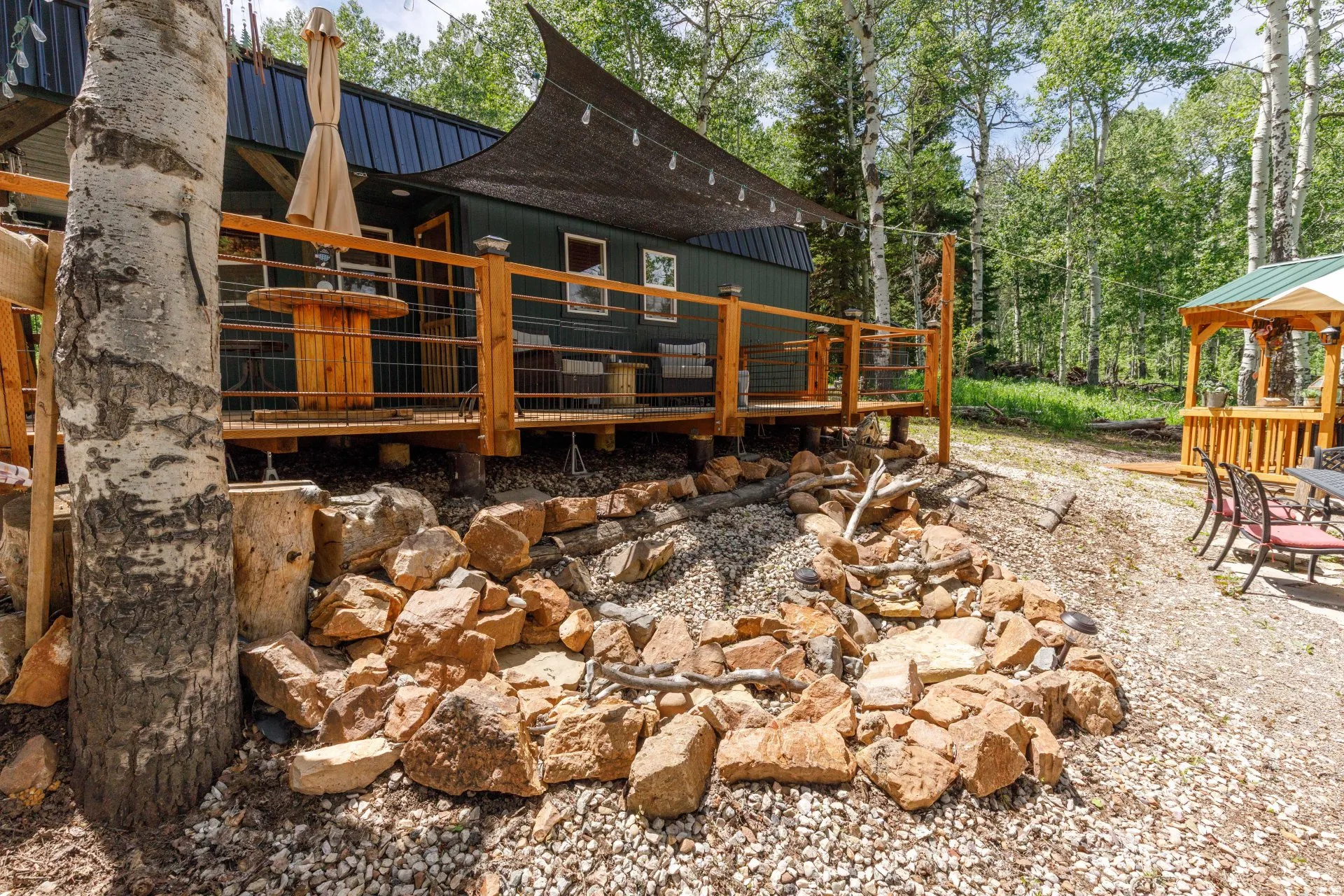 Wood-plank deck with a shade sail, accented by a rock landscape feature