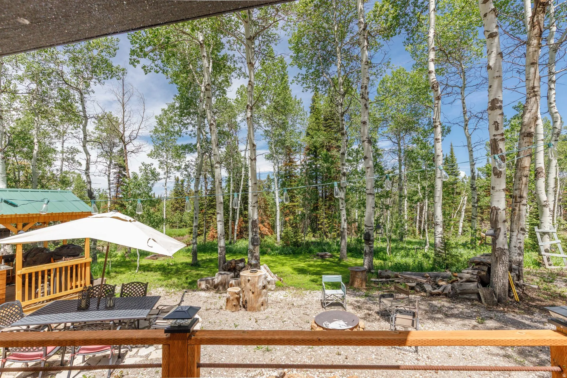 Expansive gravel patio area with a built-in fire pit, surrounded by mature trees