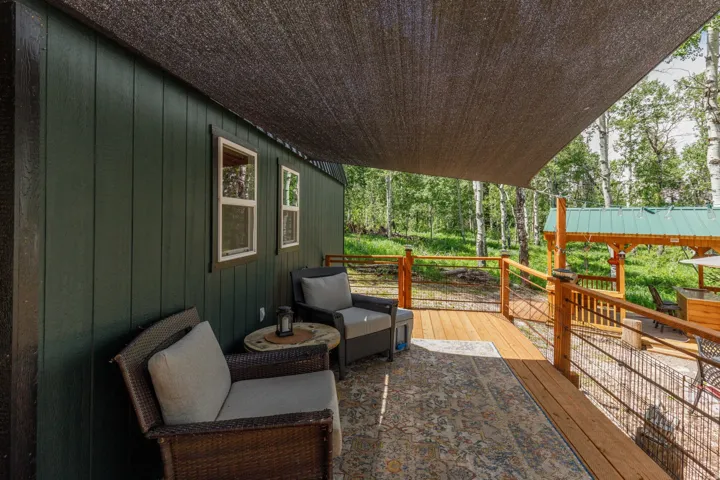 Expansive outdoor deck with a dark mesh sunshade, wood flooring, and cable railings