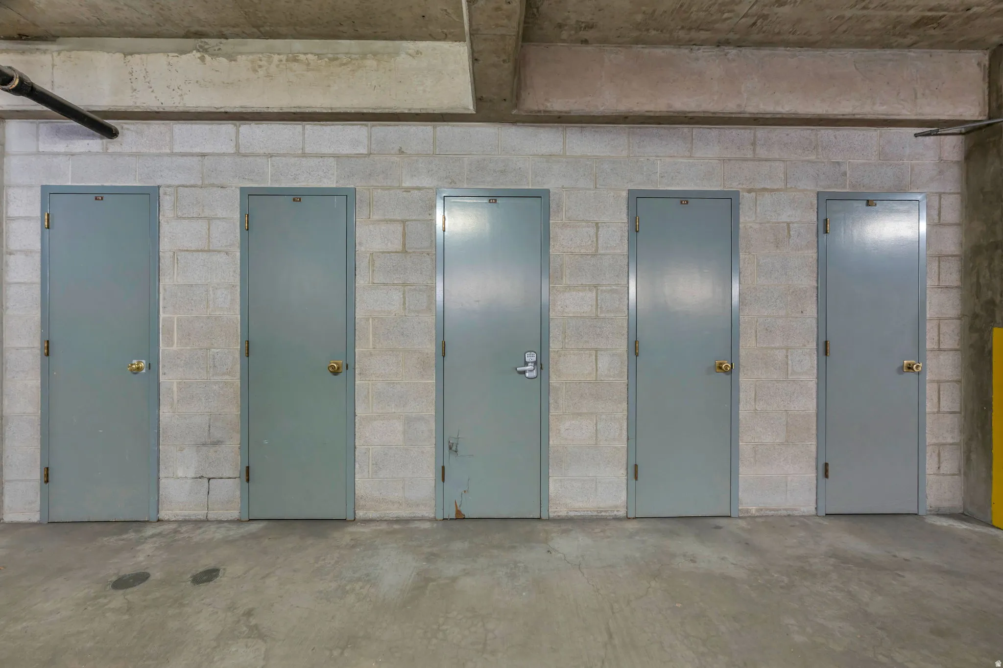 Concrete block wall storage units with grey metal doors and brass-finish hardware