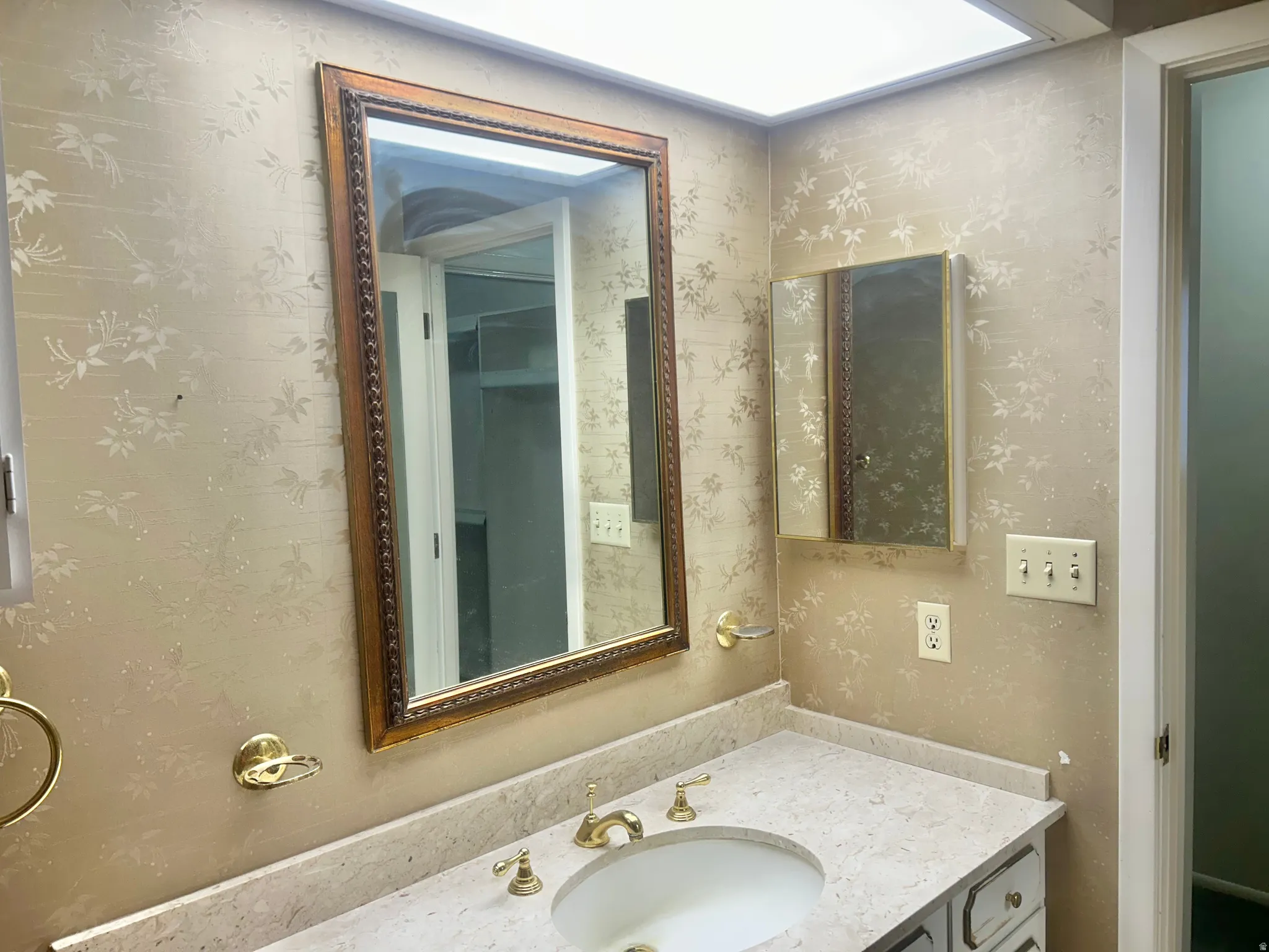 Bathroom vanity featuring a light-toned countertop with an integrated sink, brass-finish faucet, and coordinating hardware