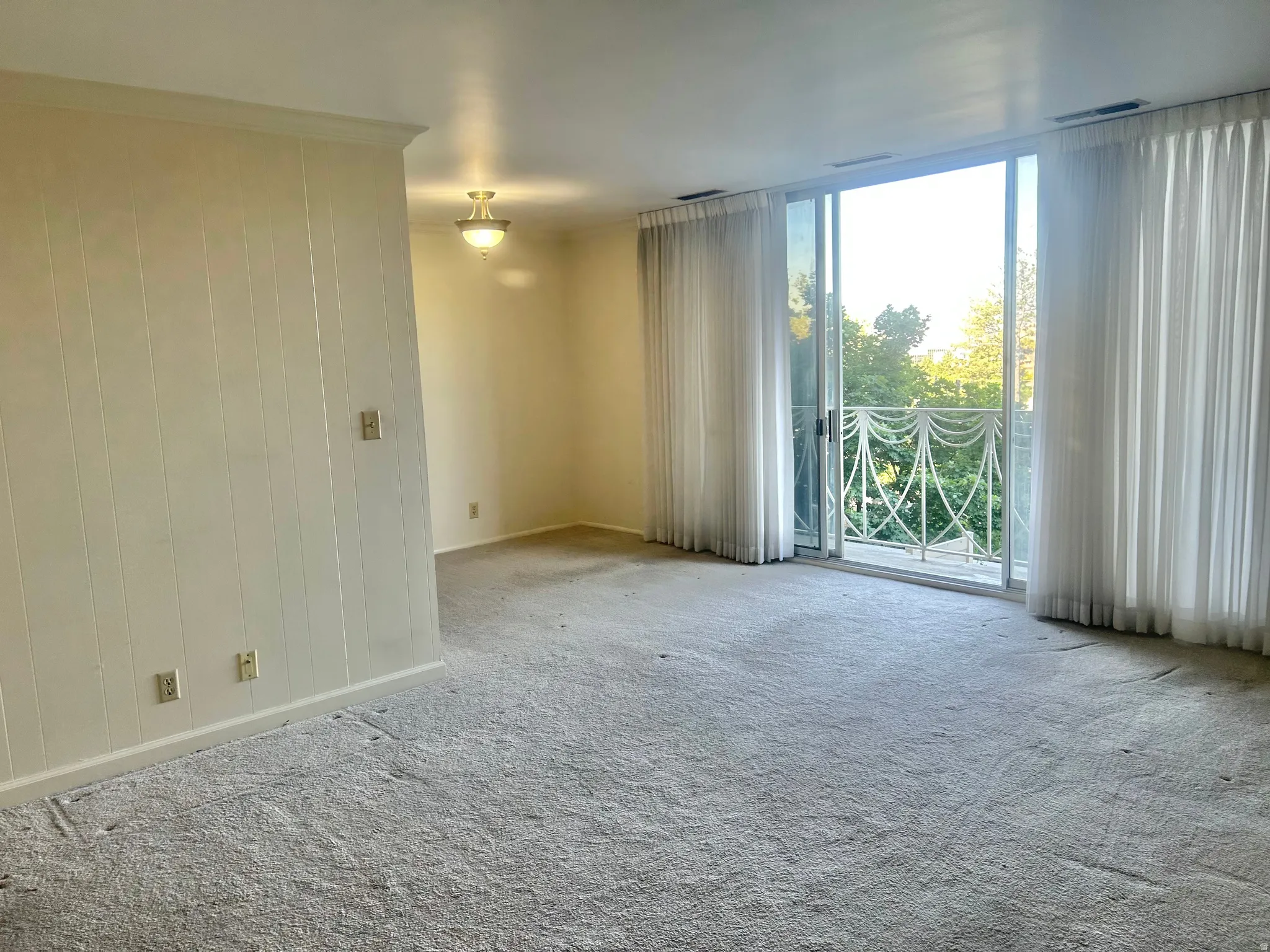 Spacious interior with neutral carpeting and vertical wall paneling