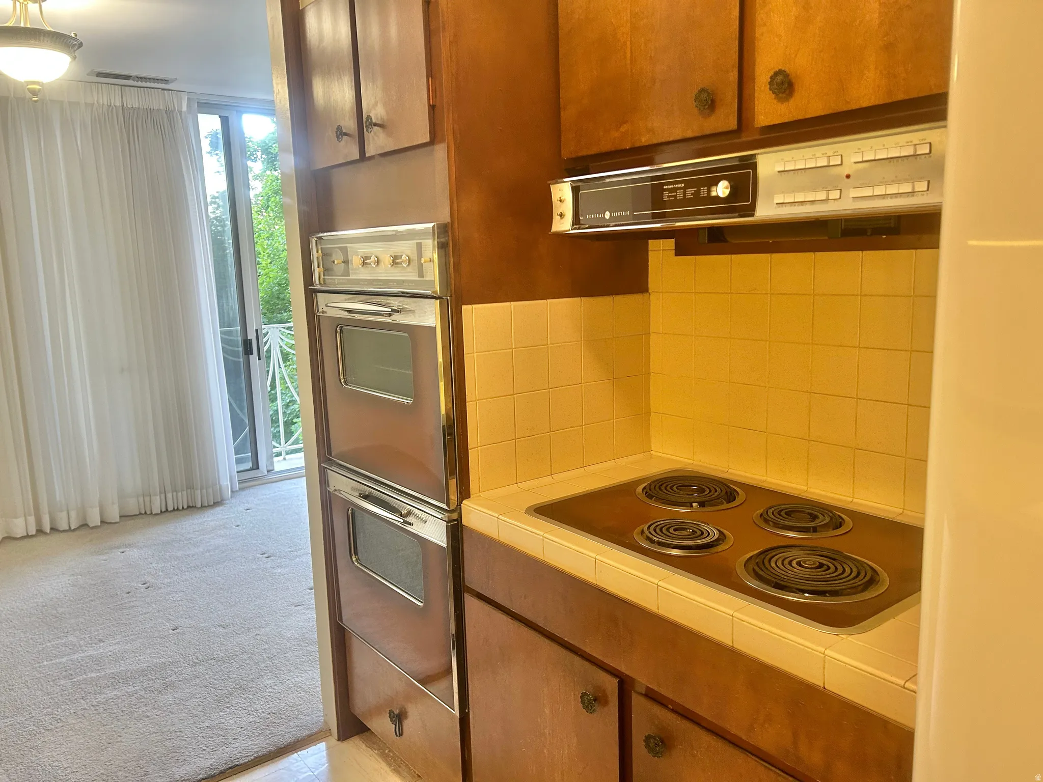 Kitchen featuring wood cabinetry, integrated double wall ovens, built-in cooktop, and a tiled backsplash