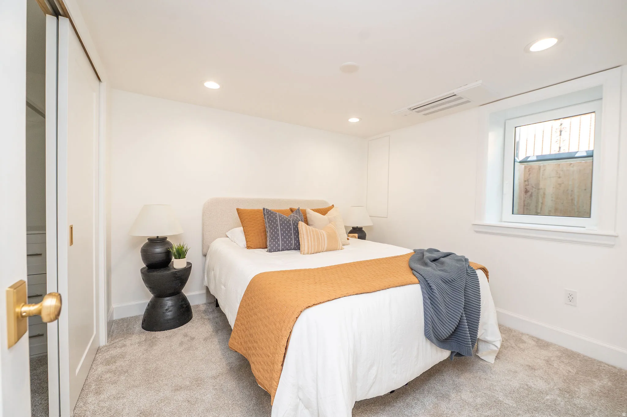 Bright bedroom featuring light-colored carpeting and white walls