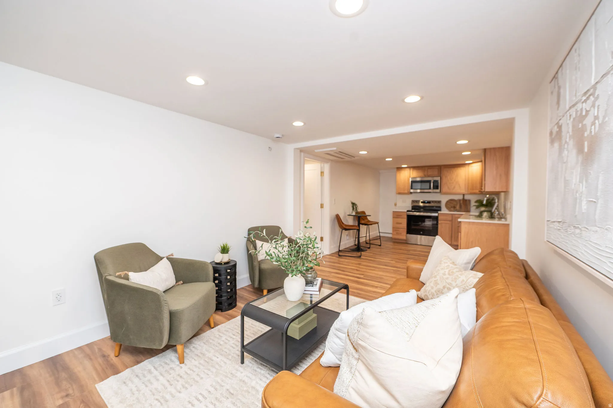 Open-concept living space featuring wood-finish flooring, recessed lighting, and a neutral color palette