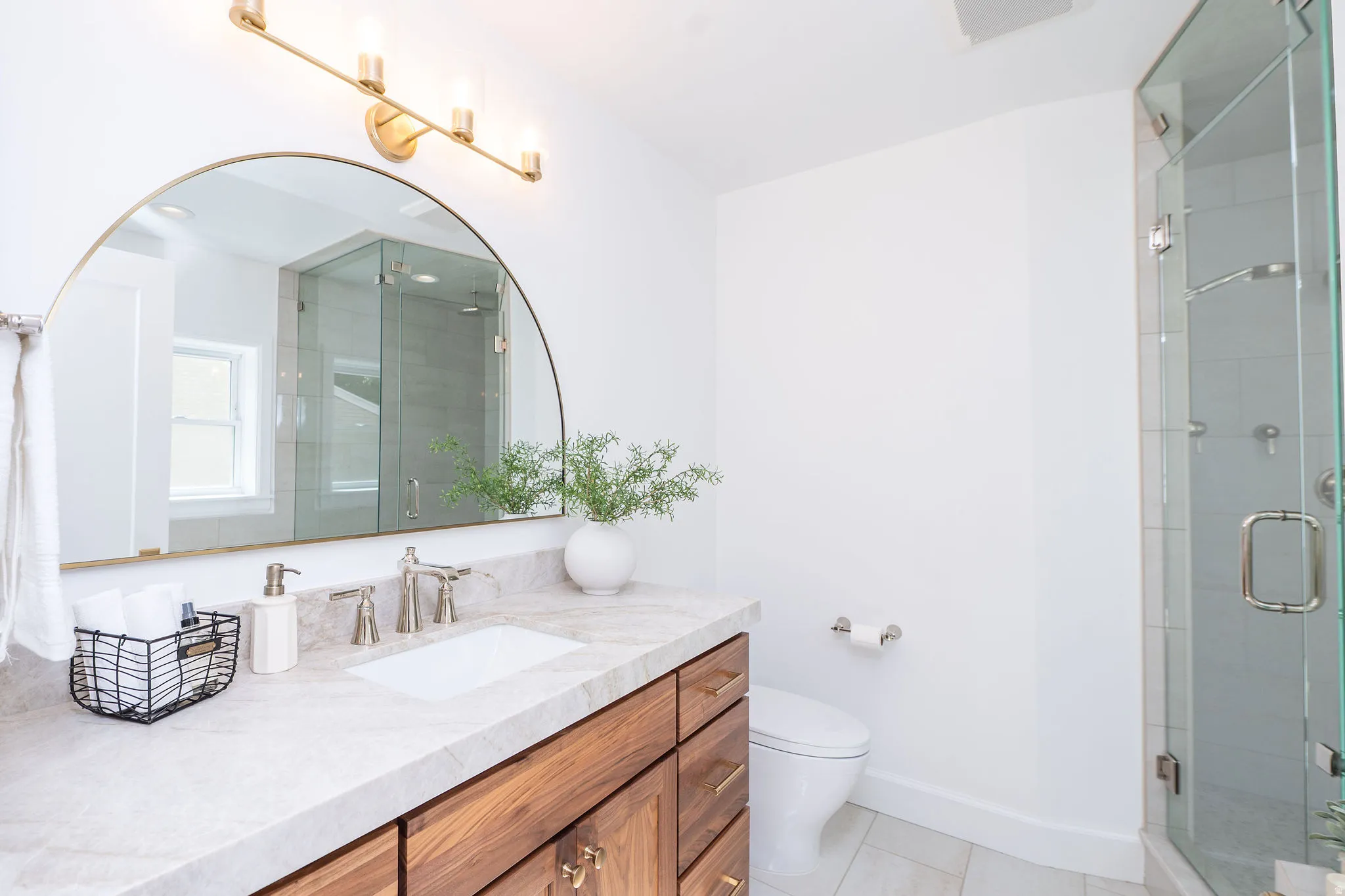 Bathroom featuring a wood-finish vanity with an undermount sink, a light-toned countertop, and brushed nickel fixtures