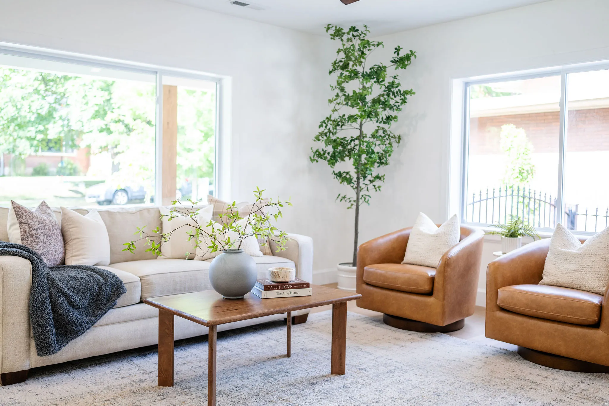 Spacious living area featuring expansive windows, light-toned walls, and wood-finish flooring