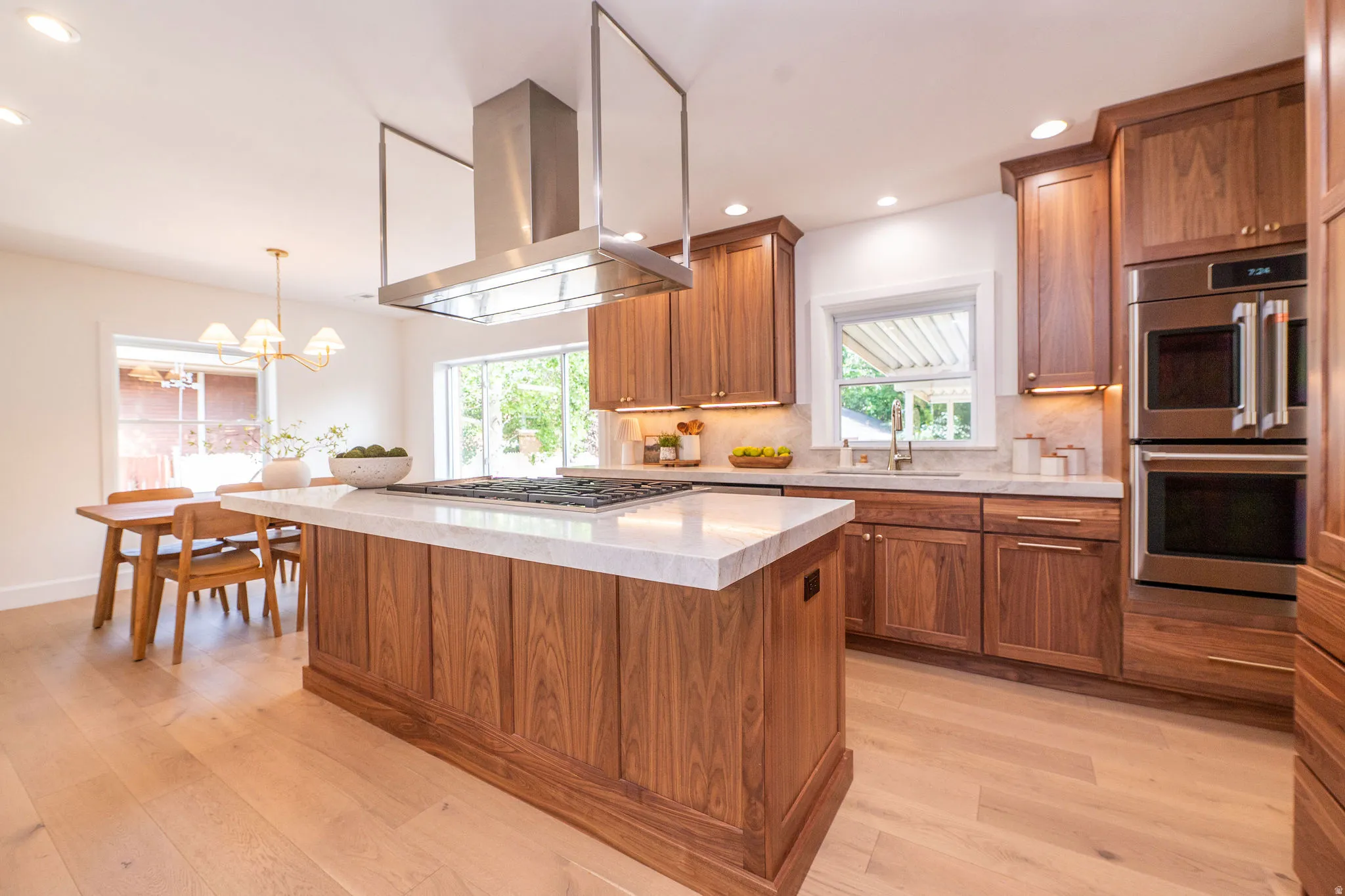 Gourmet kitchen with a large center island, rich wood-finish cabinetry, stainless steel appliances, and light wood-finish flooring