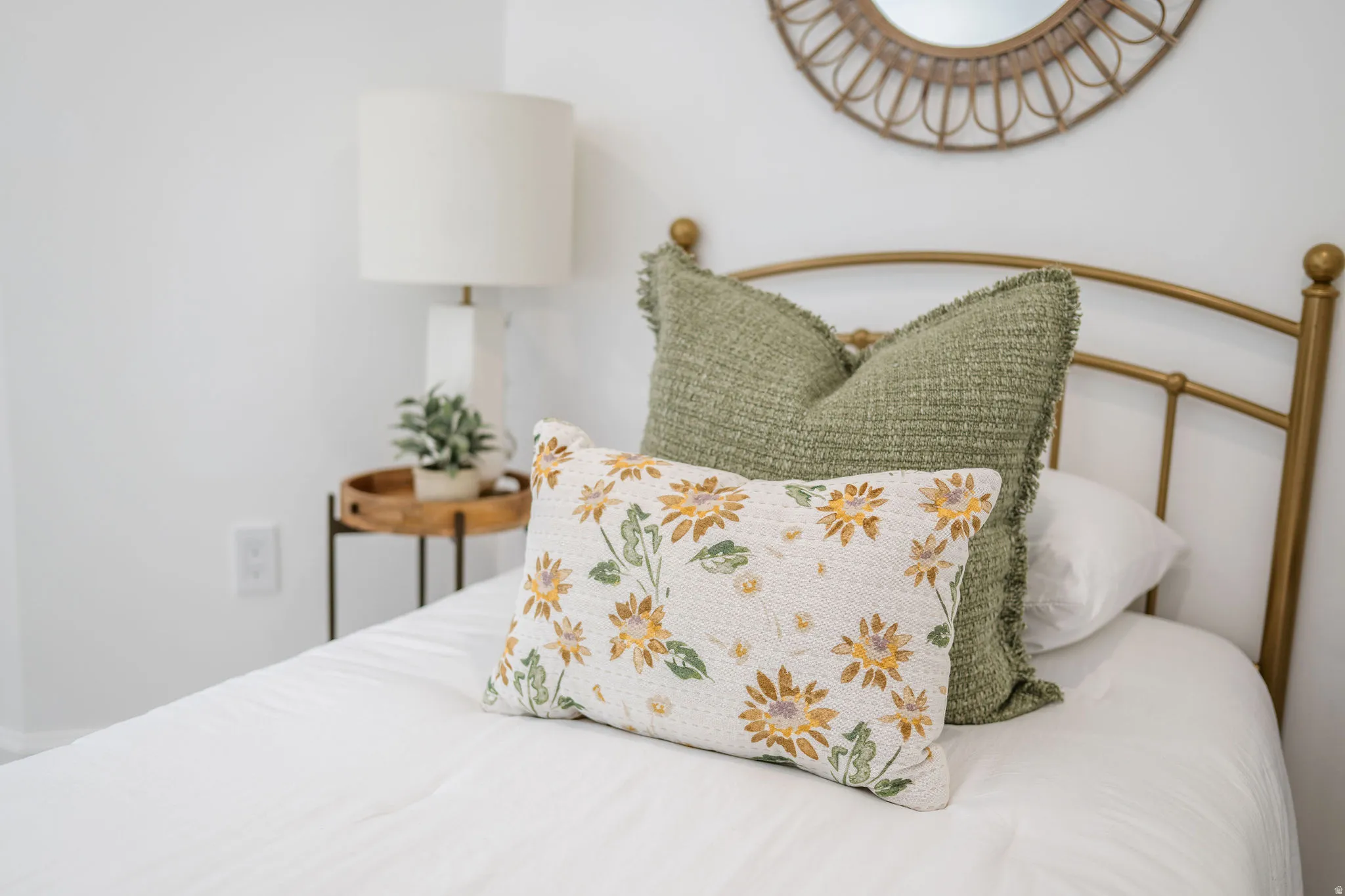 White painted wall featuring a gold-finish metal headboard