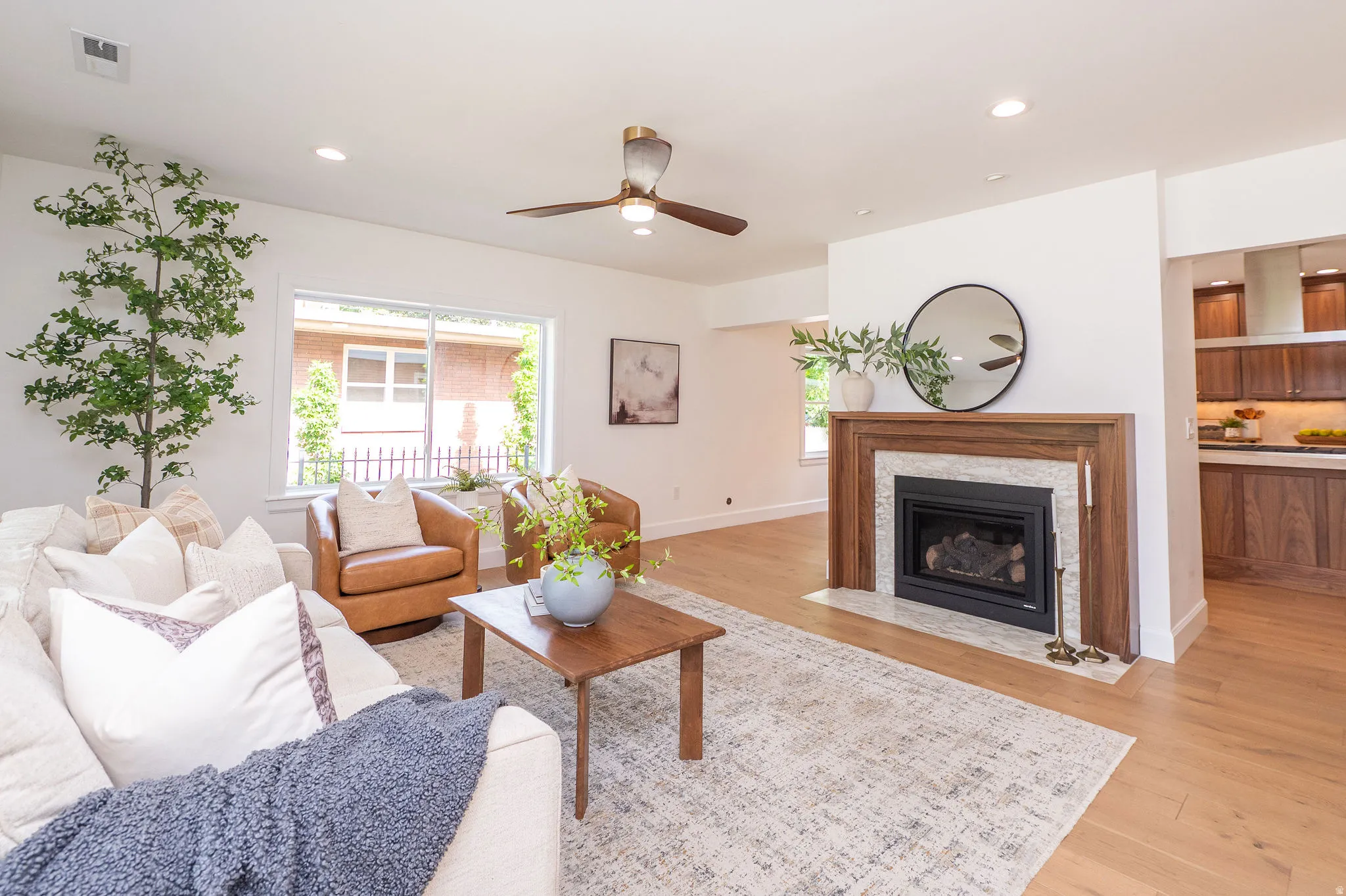 Living area featuring light wood-finish flooring, recessed lighting, and gorgeous walnut fireplace.