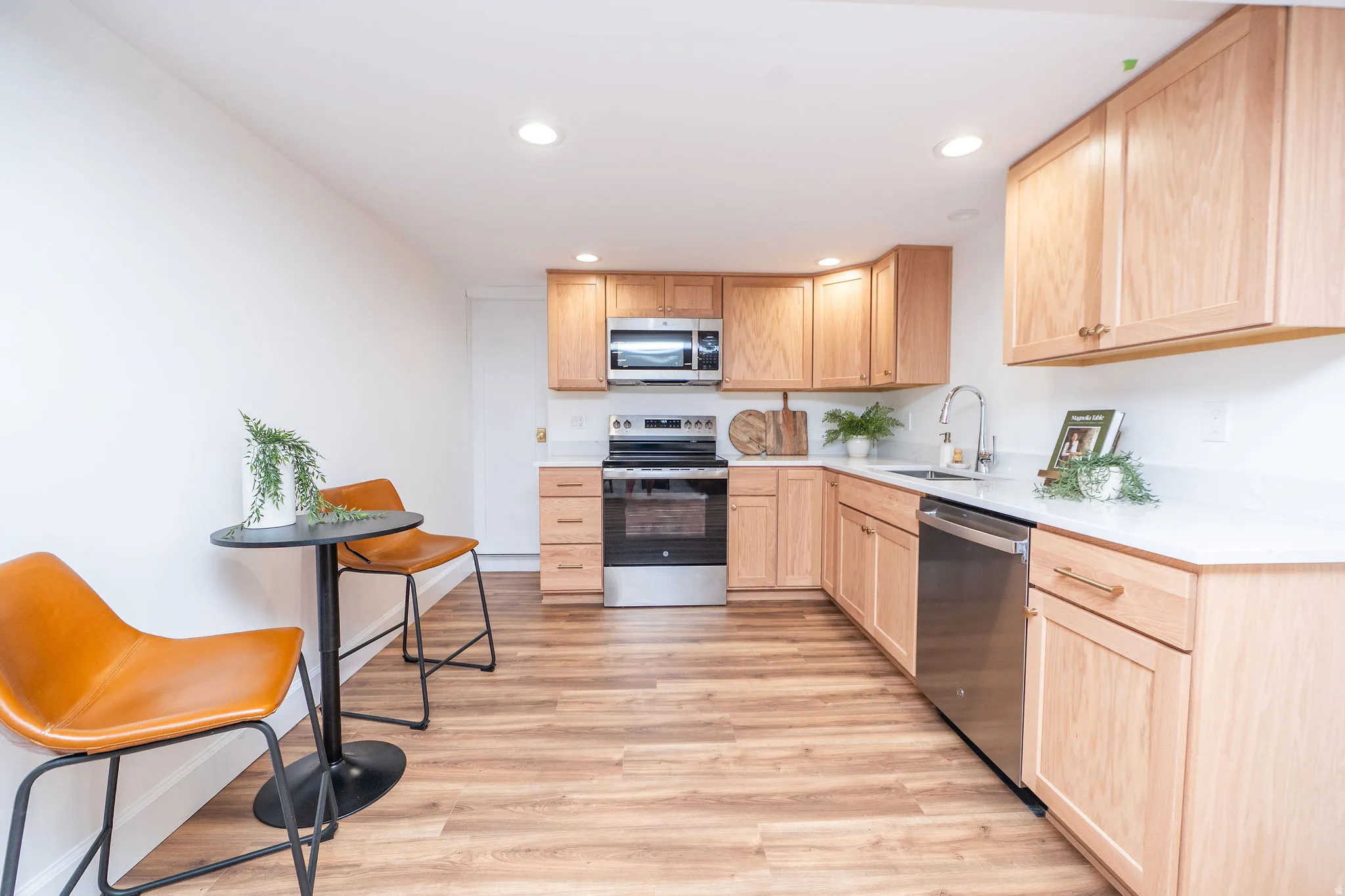 Kitchen featuring wood-finish flooring, light wood cabinetry, white countertops, and stainless steel appliances