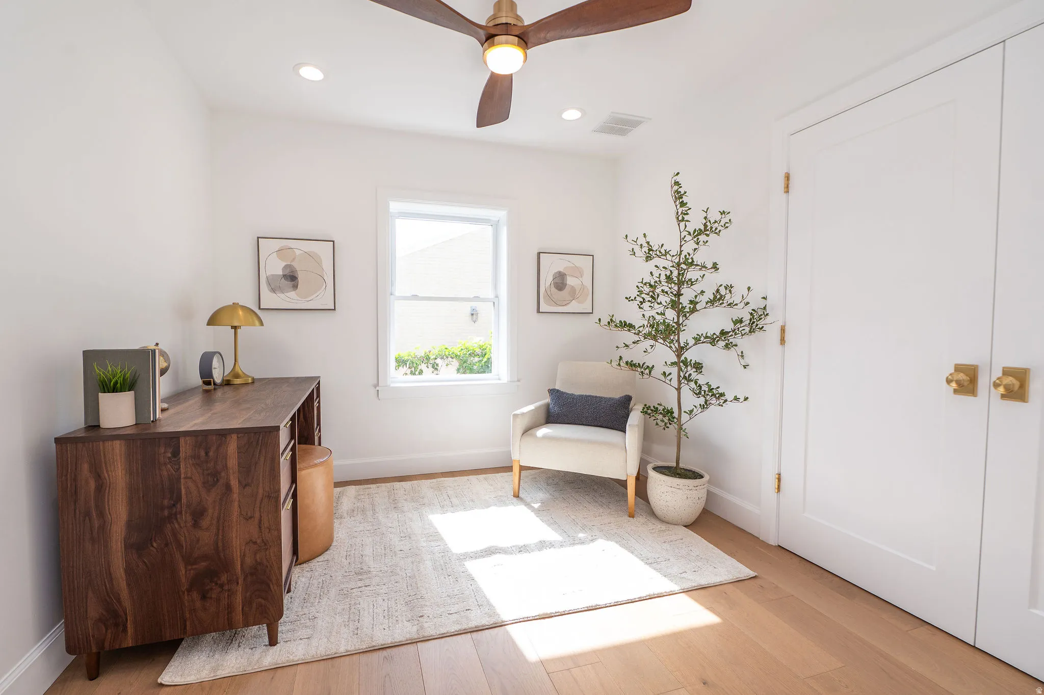 Light-filled room featuring wood-finish flooring, a ceiling fan with integrated lighting, recessed ceiling lighting, a window with natural light, and double closet doors with brass hardware