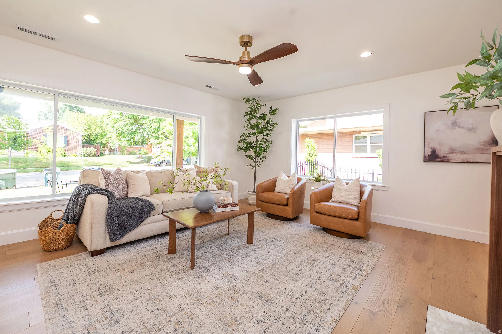 Living area featuring expansive windows, wood-finish flooring, a contemporary ceiling fan, recessed lighting, and a neutral color palette