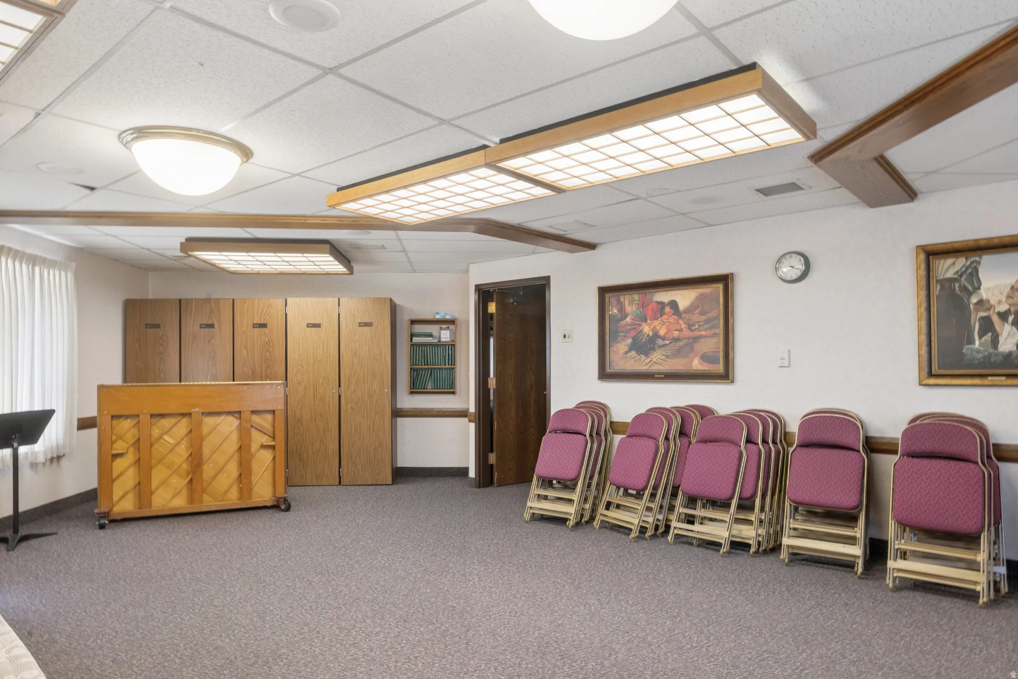Spacious room featuring neutral carpet flooring, recessed ceiling lighting, and a white acoustical tile ceiling.