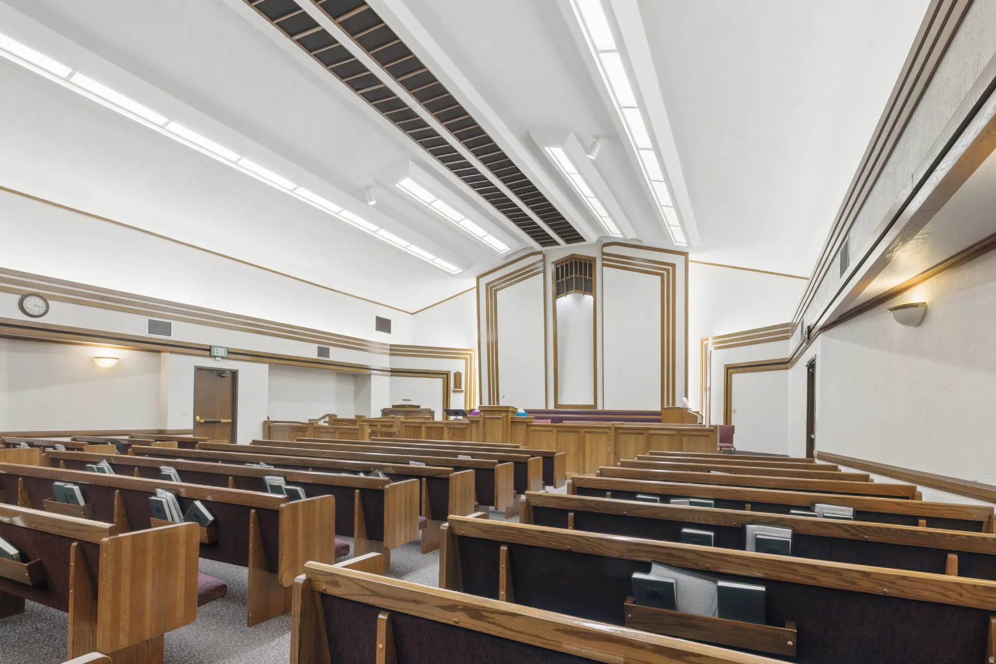 Large room with upholstered wooden benches, overhead lighting, and panel accents.