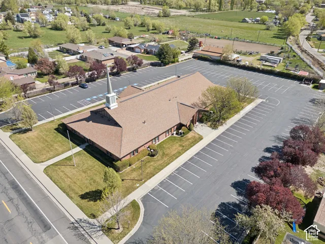 Brick building with a steeple, expansive paved parking, green lawns, and perimeter landscaping.