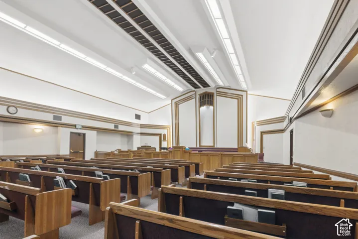 Large room with upholstered wooden benches, overhead lighting, and panel accents.