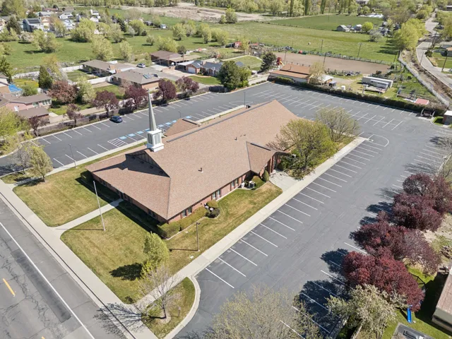 Brick building with a steeple, expansive paved parking, green lawns, and perimeter landscaping.