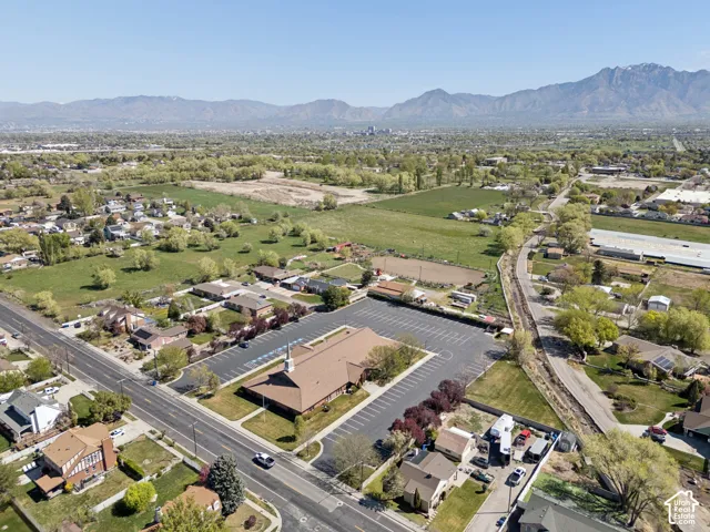 Expansive aerial perspective showcasing a neighborhood with residential properties, green spaces, and a commercial building featuring a large parking area