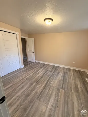 Wood-finish flooring, neutral wall paint, white trim, and a ceiling-mounted light fixture