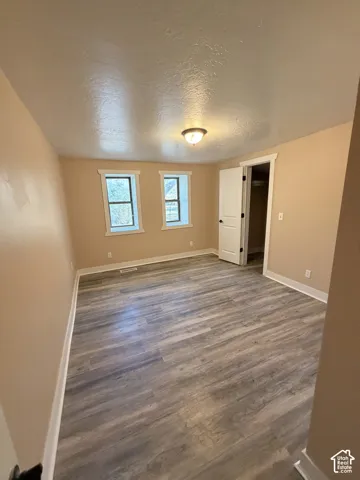 Wood-finish flooring, two windows, ceiling-mounted light fixture, and white trim accents