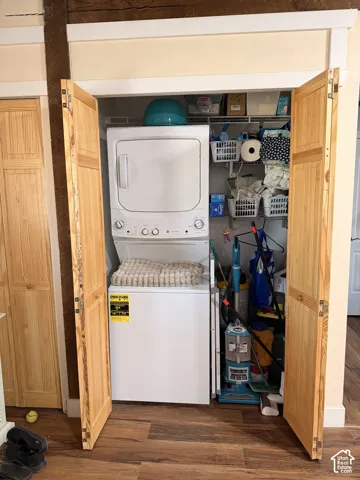 Integrated laundry closet featuring a stacked washer and dryer, bifold wood-finish doors, and overhead wire shelving