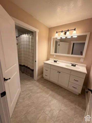 Double vanity with integrated sinks, white cabinetry, matte black hardware, and a framed mirror