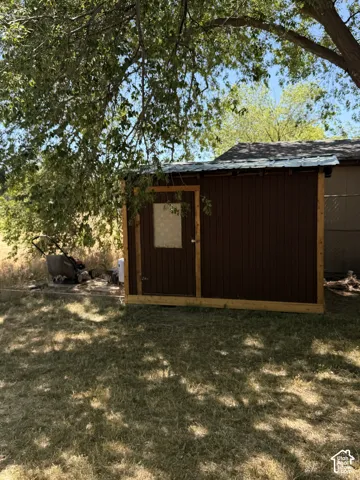 Wood-paneled shed with a metal roof and a single entry door