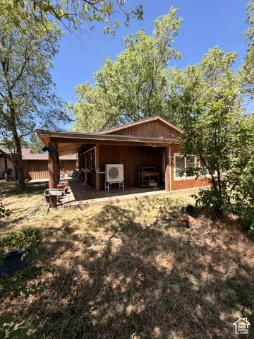 Wood-sided structure featuring an extended covered patio and multiple mature trees