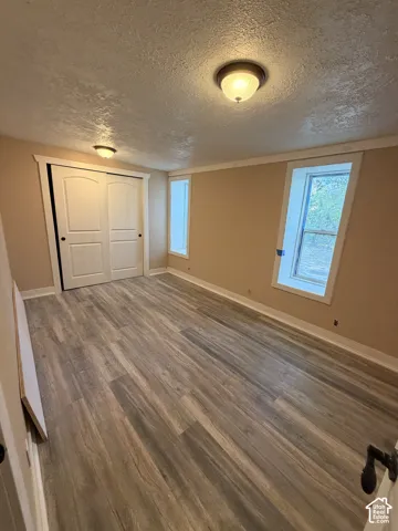 Wood-finish flooring with a neutral wall color, white trim, and a built-in closet with bifold doors