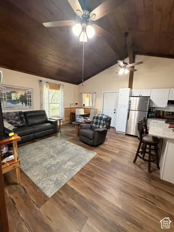 Spacious open-concept living area featuring wood-finish flooring, a vaulted wood-paneled ceiling, and multiple ceiling fans