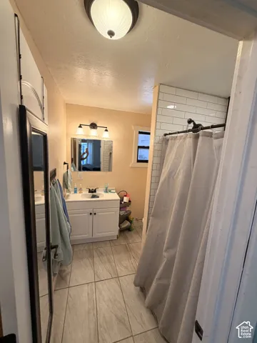Bathroom featuring a single vanity with white cabinetry, a rectangular mirror, and a wall-mounted light fixture