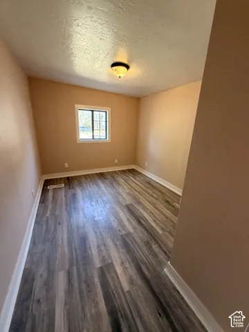 Wood-finish flooring, single window, flush-mount ceiling light fixture, neutral wall paint