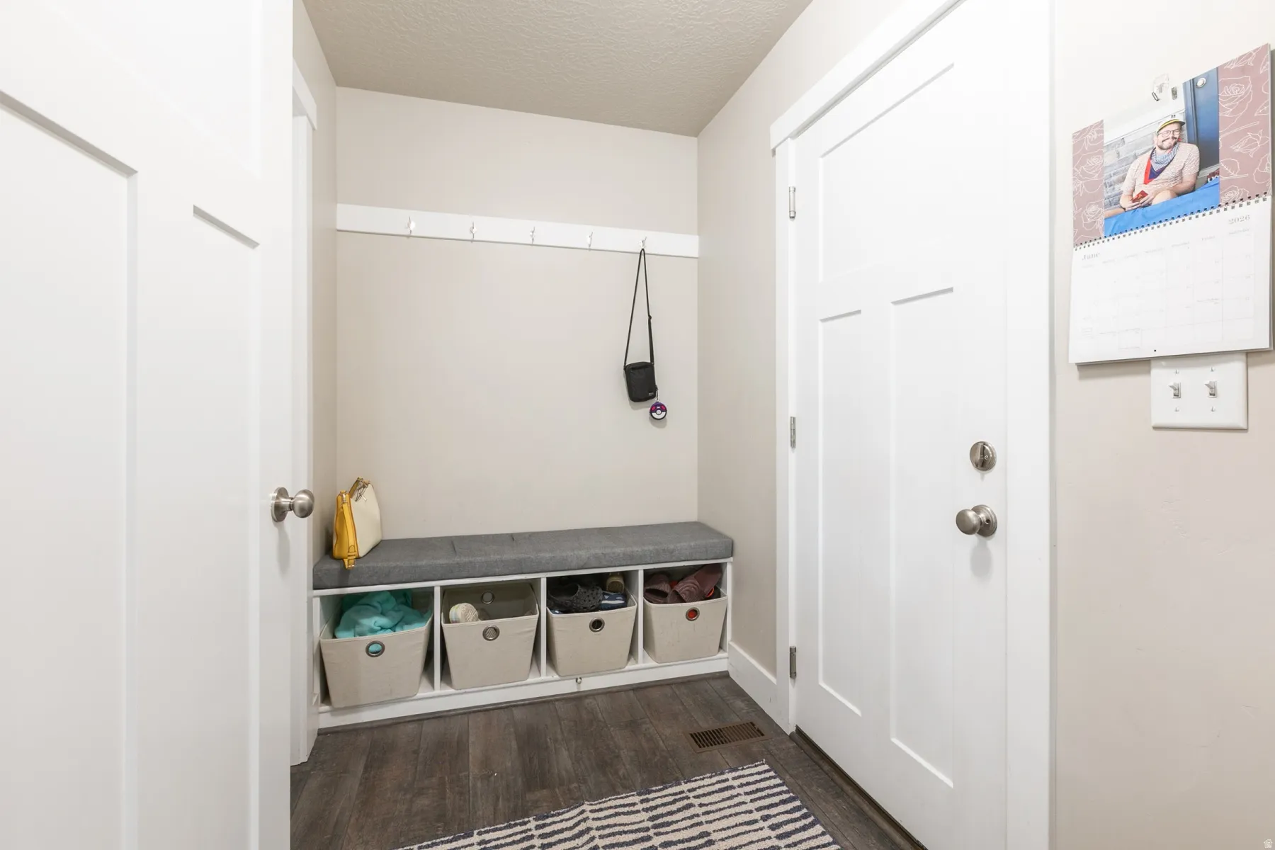 Entryway featuring wood-finish flooring, white trim, and a built-in bench with cubby storage