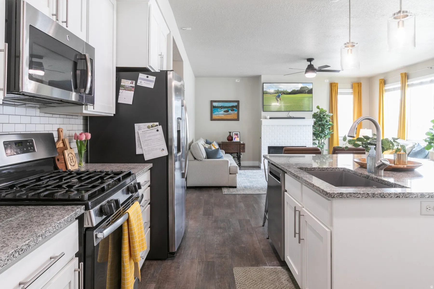 Modern kitchen featuring light cabinetry, stainless steel appliances, granite countertops, and a subway tile backsplash
