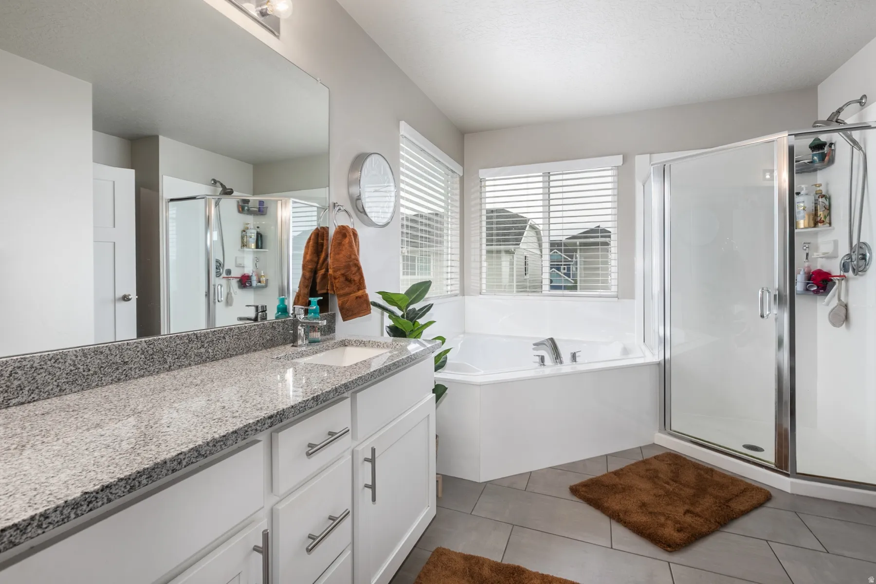 Bathroom featuring a double vanity with granite countertop, integrated single sink, and white cabinetry