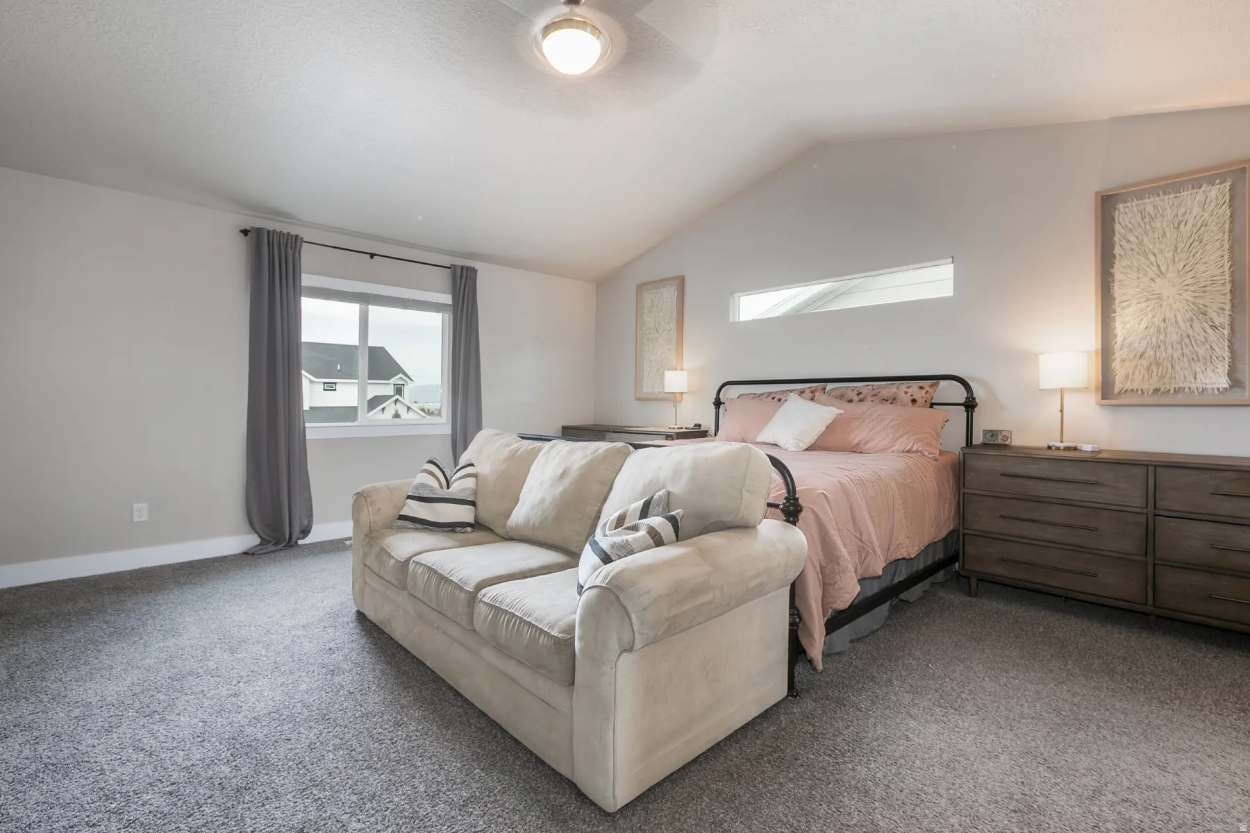 Expansive bedroom featuring vaulted ceilings, a large window with gray drapes, and plush gray carpeting