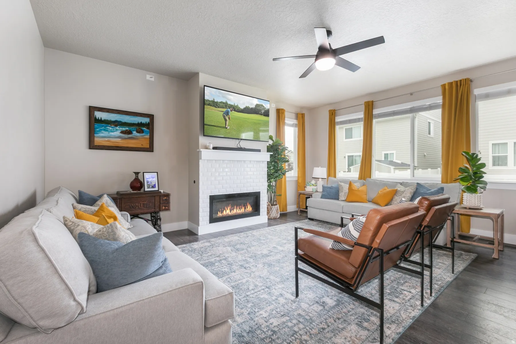Spacious living area featuring a modern linear fireplace with a white subway tile surround and mantle, dark wood-finish flooring, a contemporary ceiling fan, and multiple windows with blinds