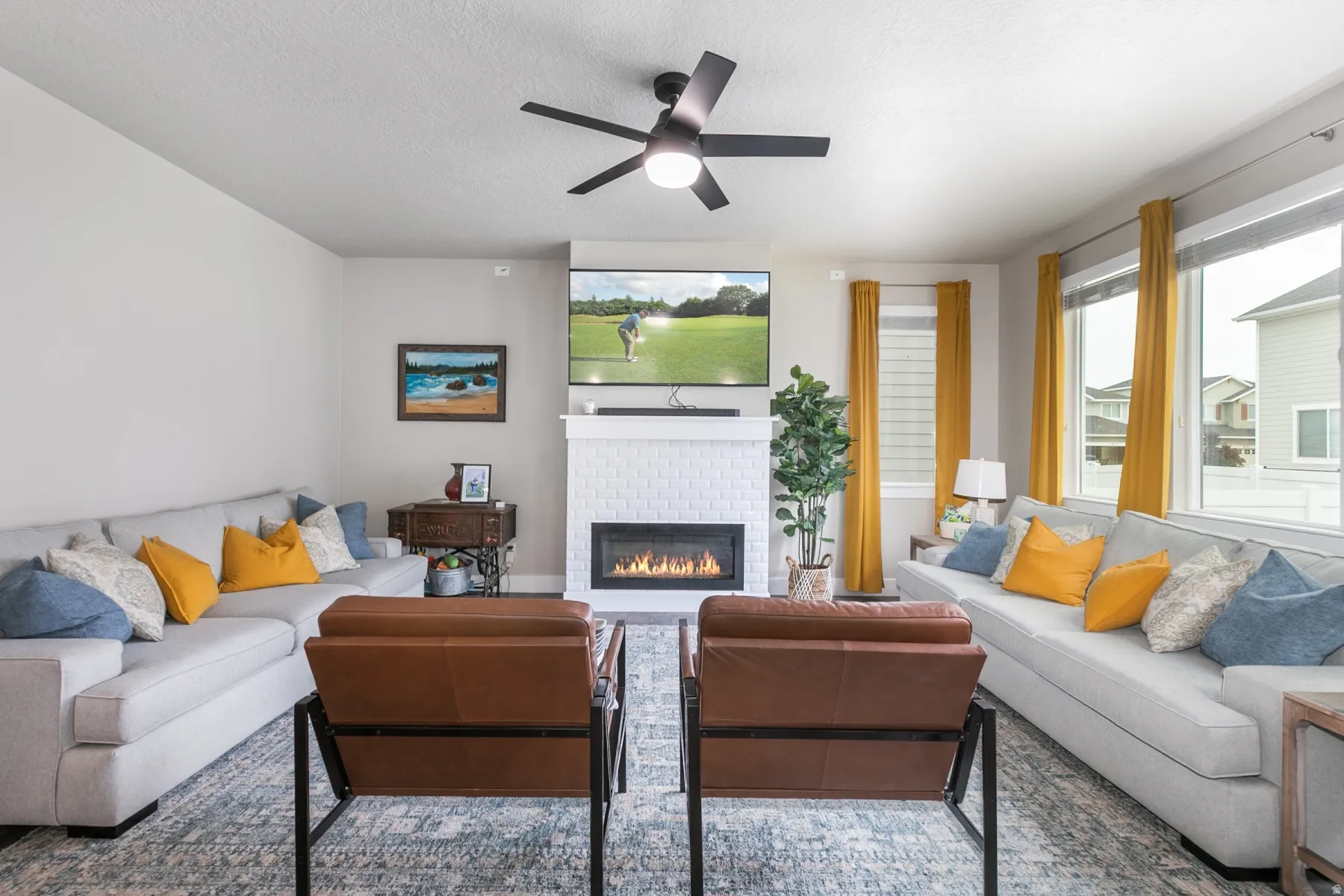 Living space with a white brick fireplace, mounted television, and a ceiling fan